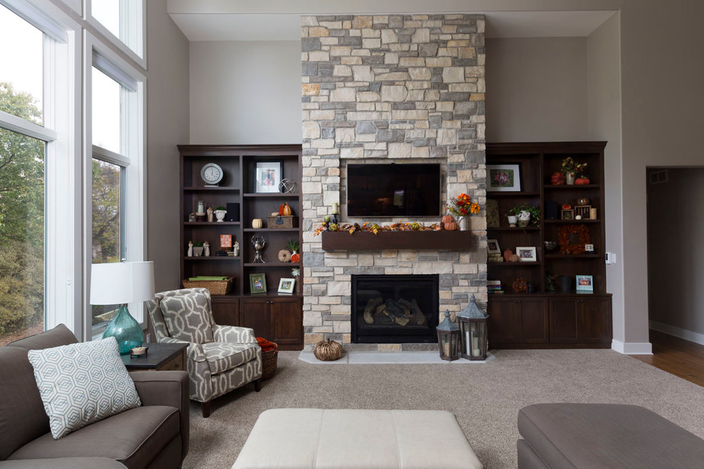 Foto de sala de estar abierta tradicional renovada grande con paredes marrones, moqueta, todas las chimeneas, marco de chimenea de piedra y televisor colgado en la pared