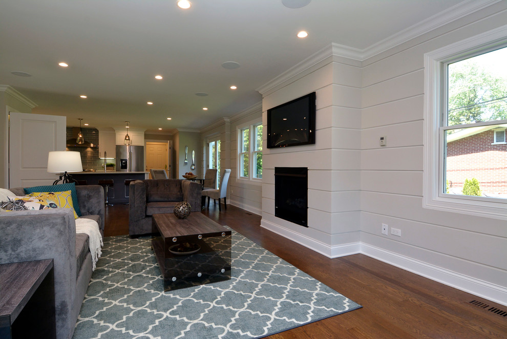 Mittelgroßes, Offenes Klassisches Wohnzimmer mit grauer Wandfarbe, braunem Holzboden, Kamin, Kaminumrandung aus Holz, TV-Wand und braunem Boden in Chicago