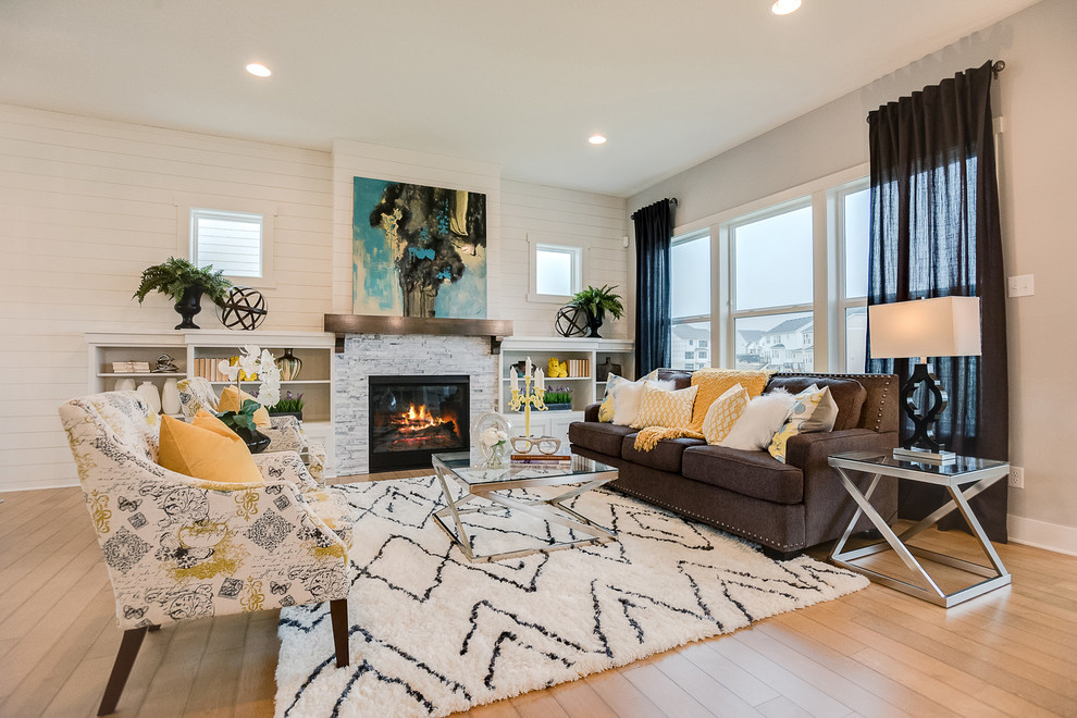 Offenes Klassisches Wohnzimmer mit beiger Wandfarbe, braunem Holzboden, Kamin und Kaminumrandung aus Stein in Minneapolis