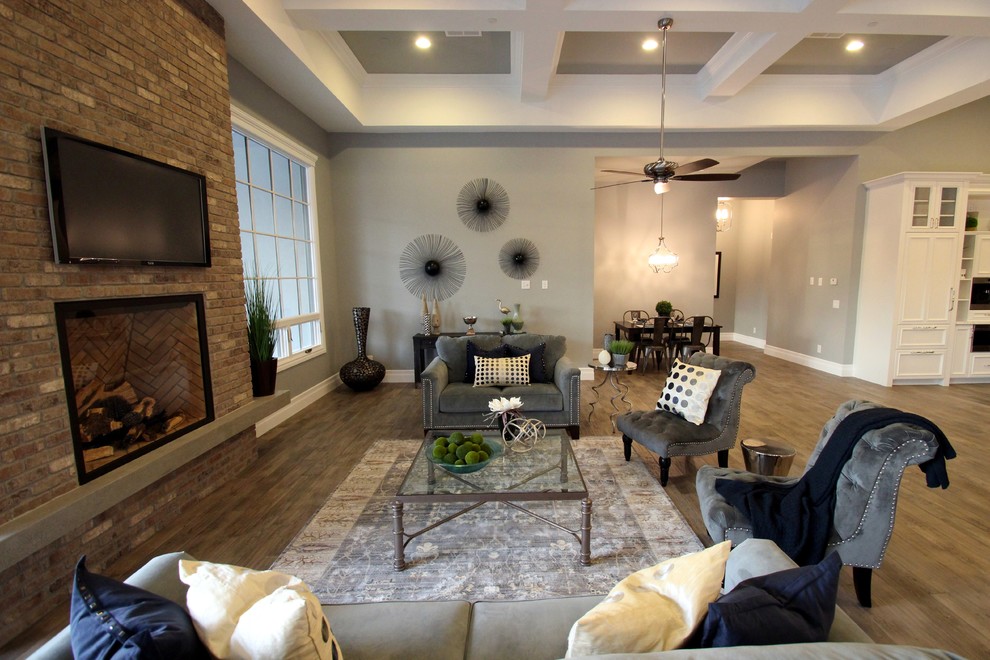 Идея дизайна: открытая гостиная комната в стиле неоклассика (современная классика) с серыми стенами, ковровым покрытием, телевизором на стене, стандартным камином и фасадом камина из кирпича
