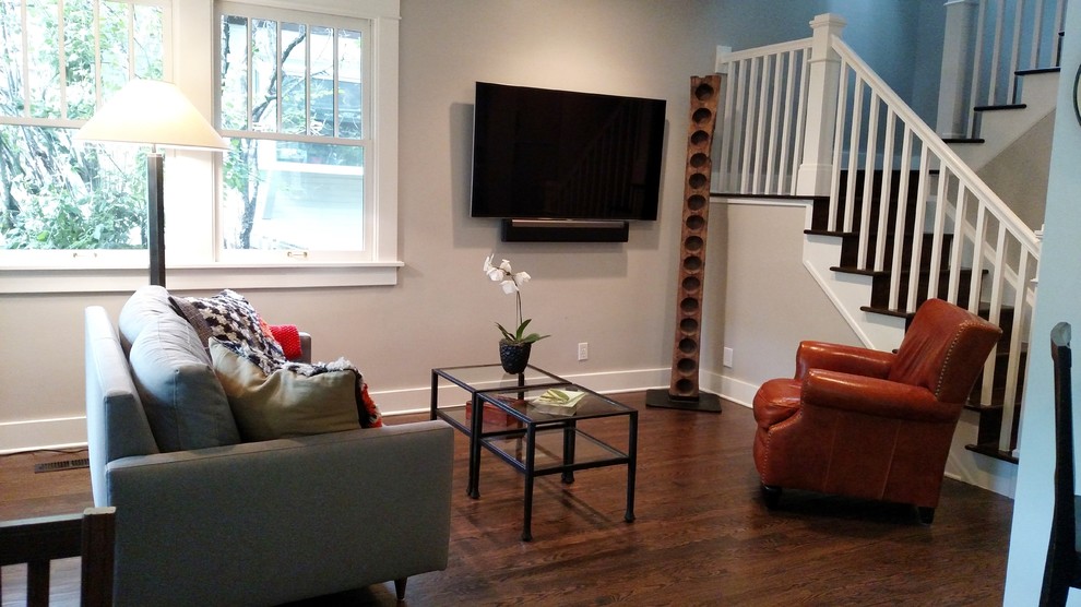 Modelo de sala de estar cerrada clásica renovada pequeña con paredes grises, suelo de madera oscura y televisor colgado en la pared