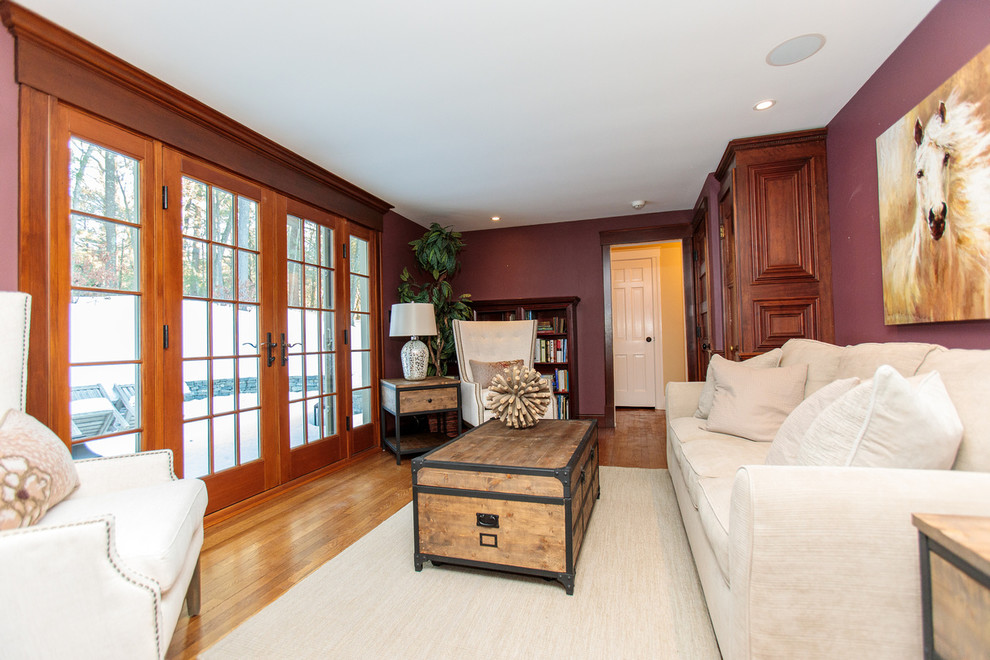 Example of a mid-sized classic enclosed medium tone wood floor family room library design in Boston with purple walls