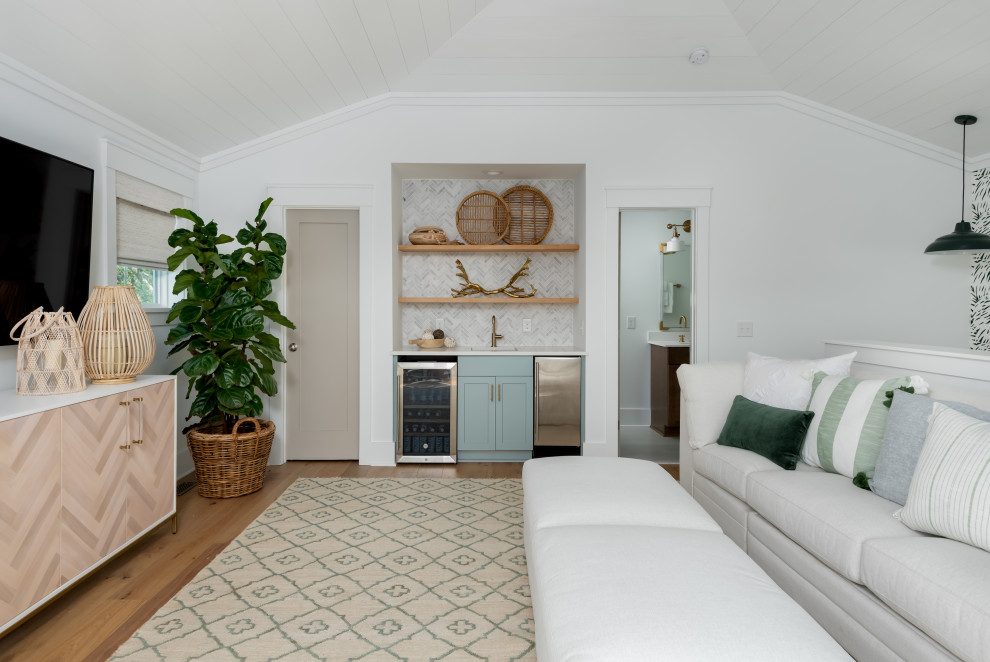 Immagine di un soggiorno tropicale di medie dimensioni e stile loft con angolo bar, pareti verdi, parquet chiaro e TV a parete