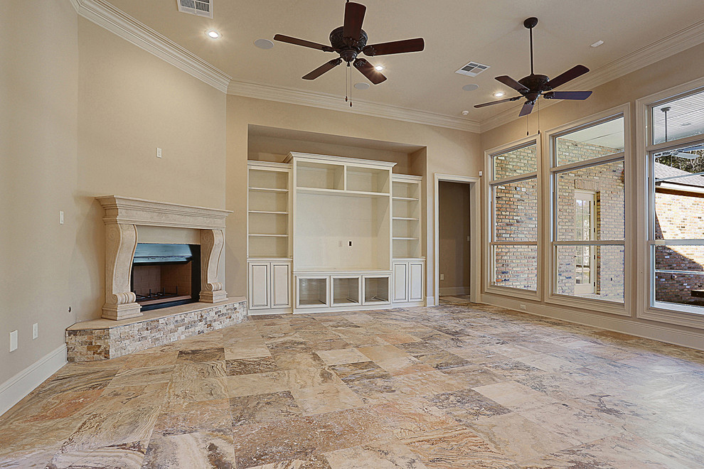 Foto de sala de estar abierta clásica con paredes beige, suelo de travertino, chimenea de esquina, marco de chimenea de piedra y pared multimedia
