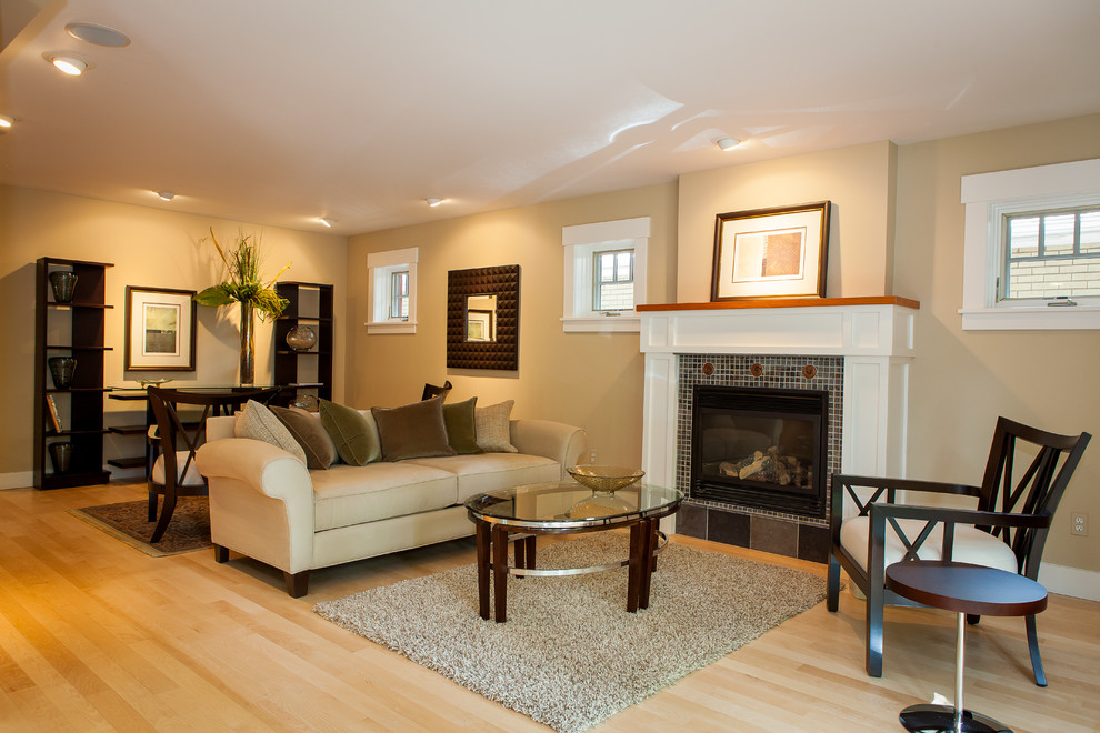 Photo of a medium sized contemporary open plan games room in Denver with light hardwood flooring, a standard fireplace, a plastered fireplace surround, beige walls and beige floors.