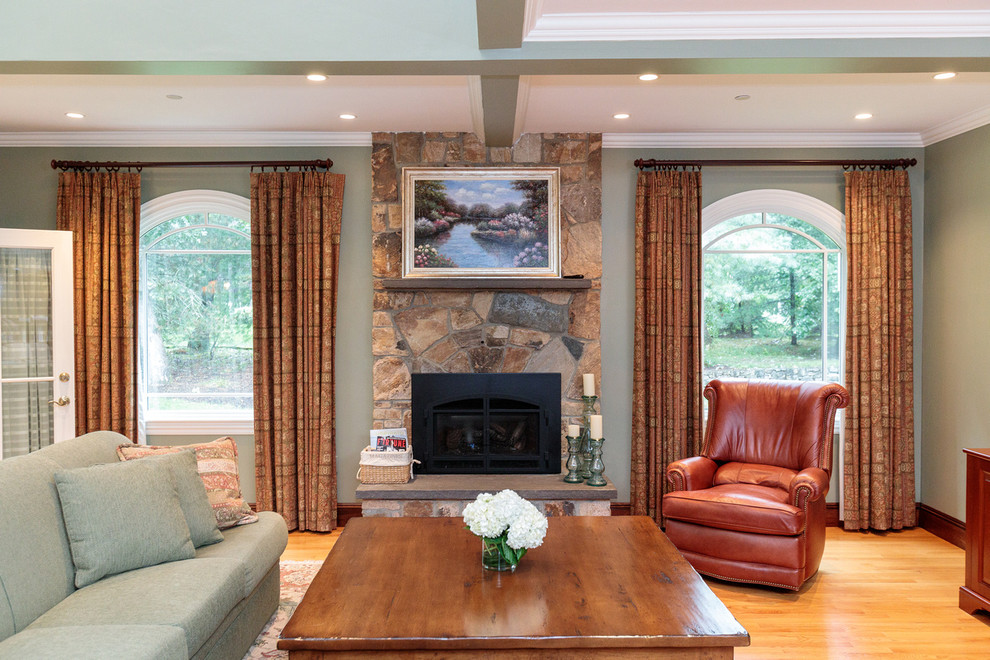 Imagen de sala de estar abierta clásica extra grande con paredes verdes, suelo de madera clara, todas las chimeneas y marco de chimenea de piedra