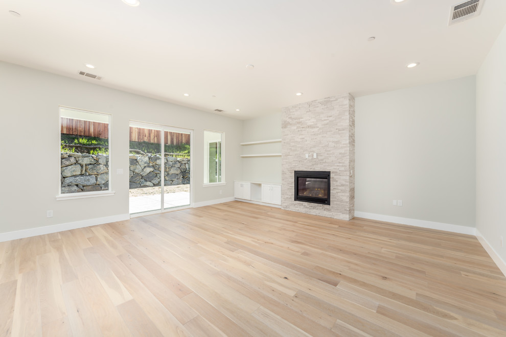 Small contemporary open plan games room in Sacramento with grey walls, light hardwood flooring, a standard fireplace, a stone fireplace surround, a built-in media unit and beige floors.