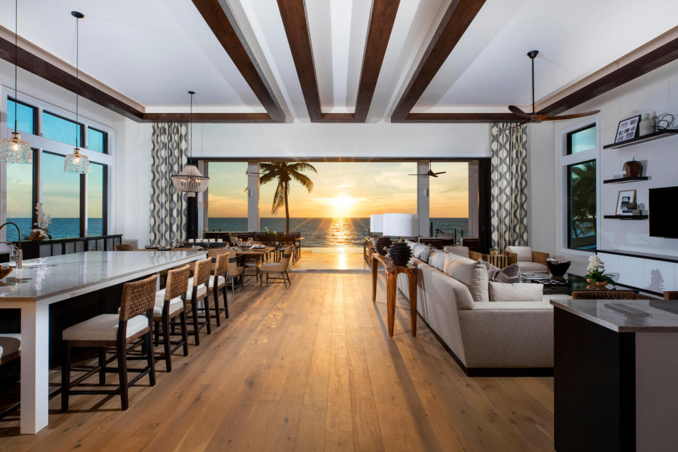 Idee per un soggiorno tropicale di medie dimensioni e aperto con pareti beige, pavimento in legno massello medio, TV a parete e pavimento marrone