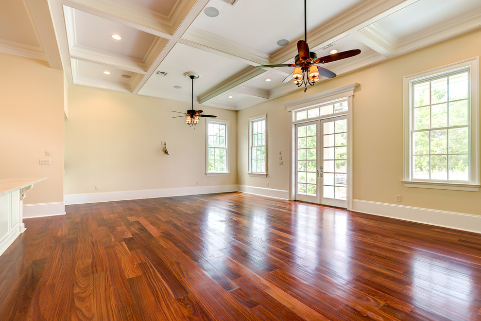 Imagen de sala de estar abierta tradicional extra grande sin chimenea con paredes amarillas y suelo de madera en tonos medios