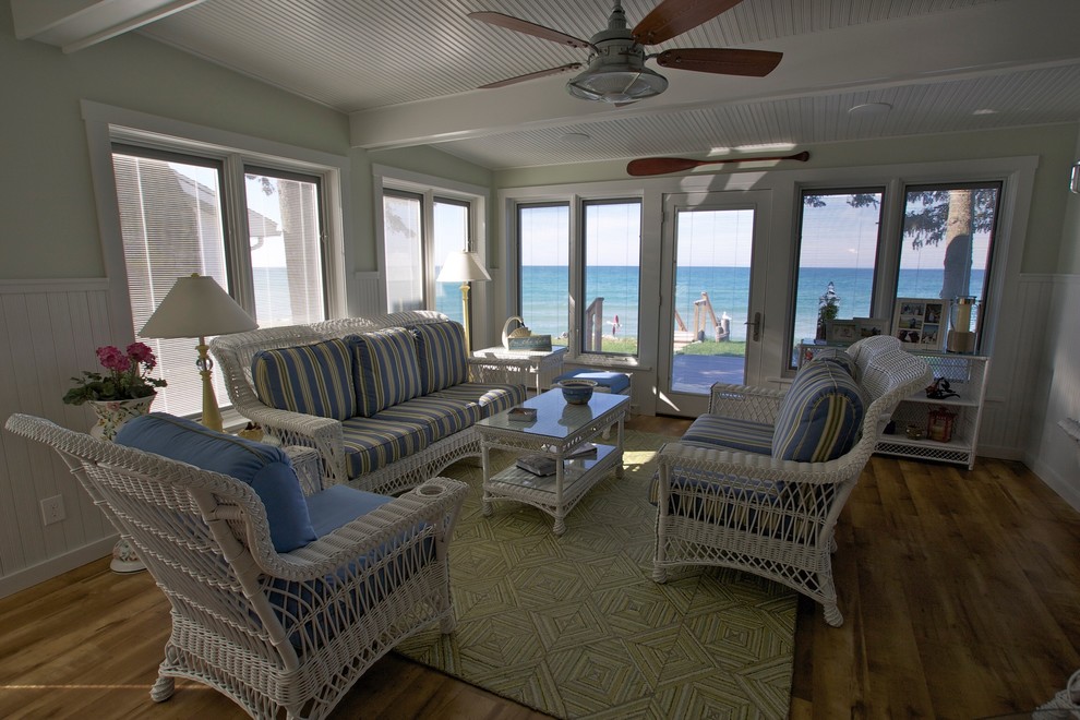 Imagen de sala de estar abierta costera de tamaño medio sin chimenea con paredes verdes y suelo de madera en tonos medios