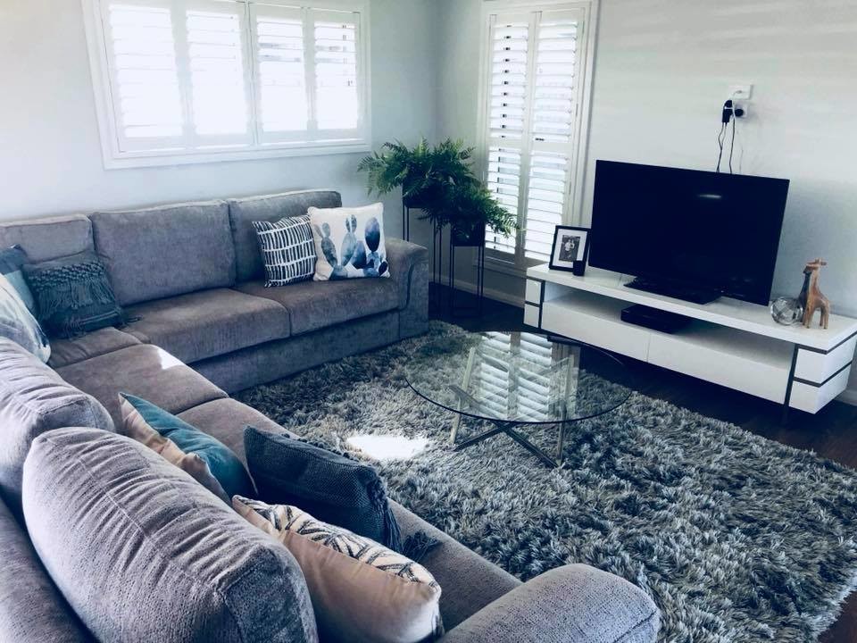 Modelo de sala de estar abierta moderna de tamaño medio con paredes grises, suelo laminado y televisor colgado en la pared