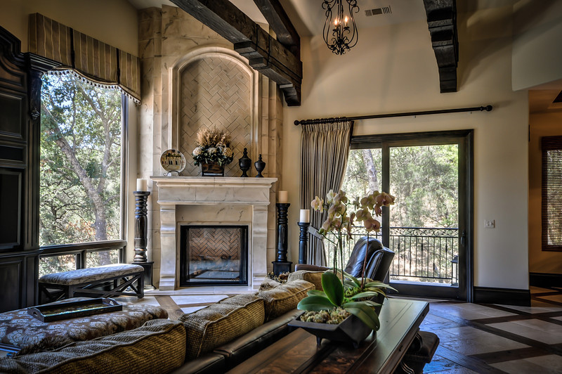 Photo of a large mediterranean open plan games room in Sacramento with limestone flooring, a corner fireplace, a stone fireplace surround, a concealed tv and beige floors.