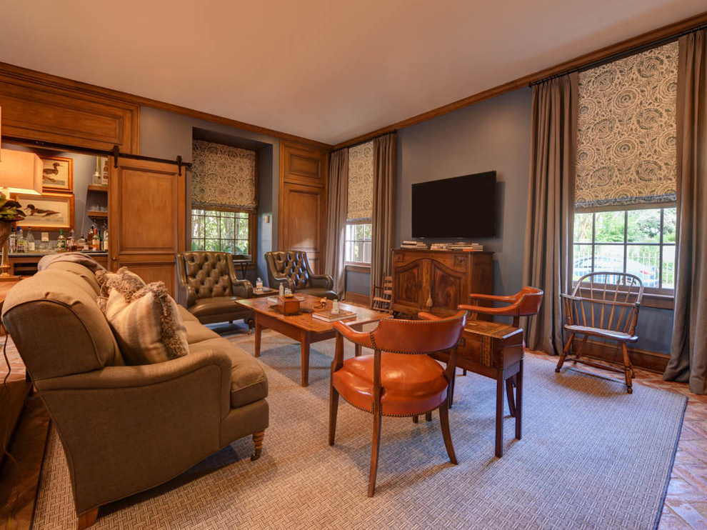 На фото: большая открытая гостиная комната в классическом стиле с синими стенами, кирпичным полом, стандартным камином, фасадом камина из дерева, телевизором на стене и коричневым полом