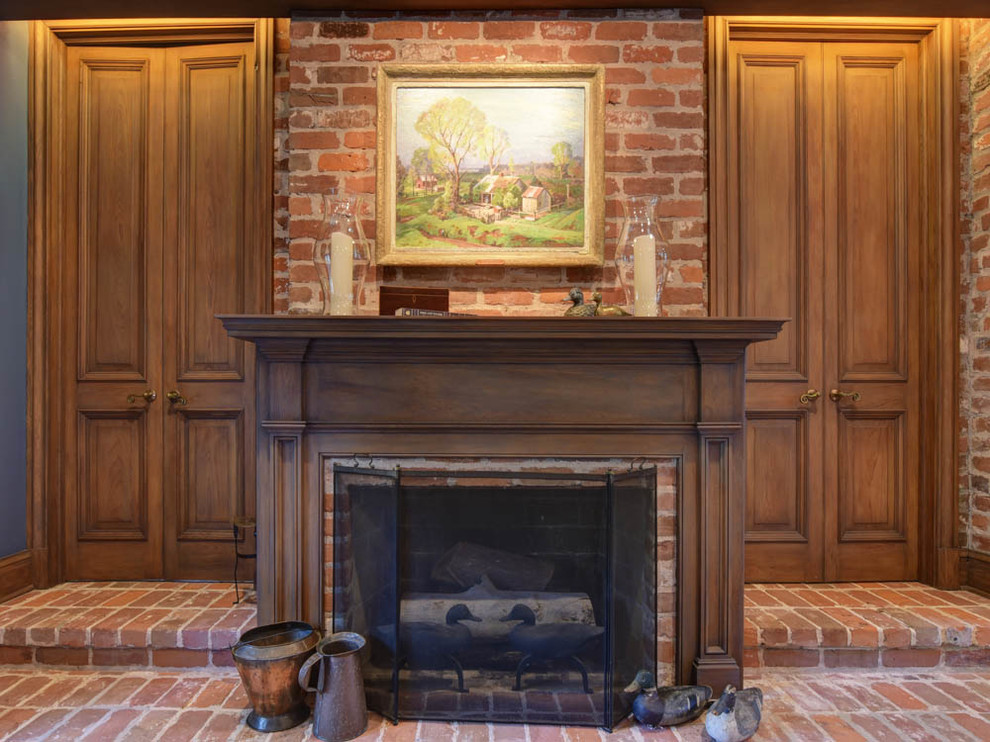 Пример оригинального дизайна: большая открытая гостиная комната в классическом стиле с синими стенами, кирпичным полом, стандартным камином, фасадом камина из дерева, телевизором на стене и коричневым полом