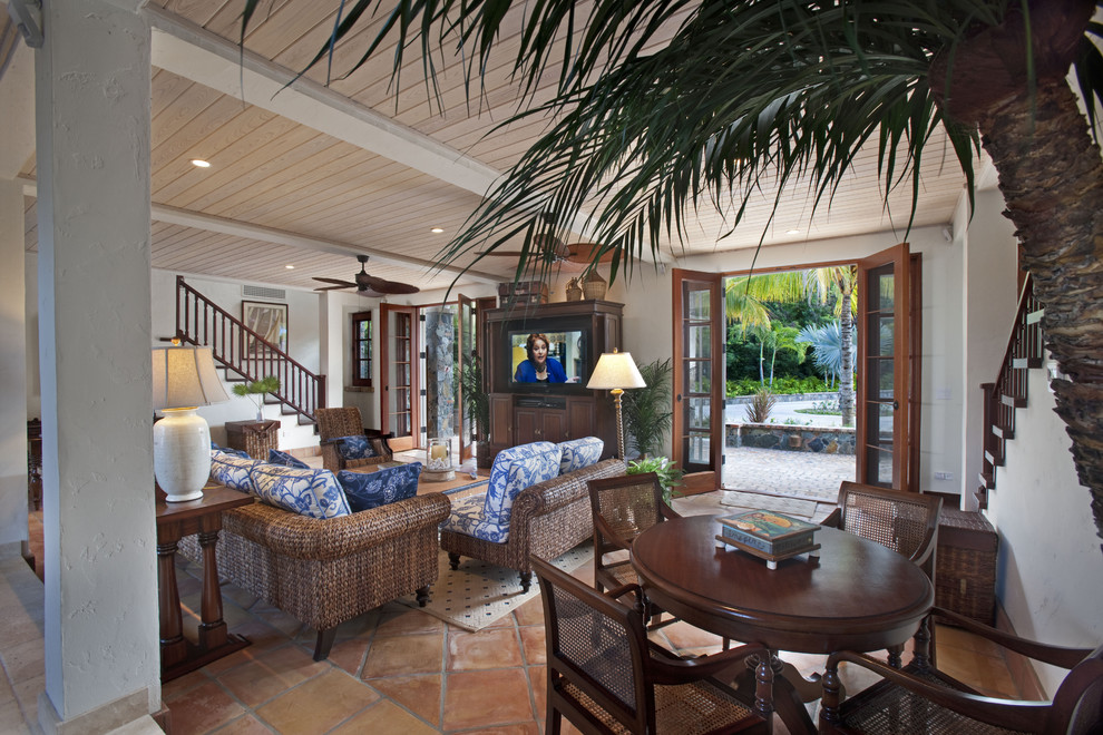 Diseño de sala de estar tropical con paredes beige, suelo de baldosas de terracota y televisor independiente