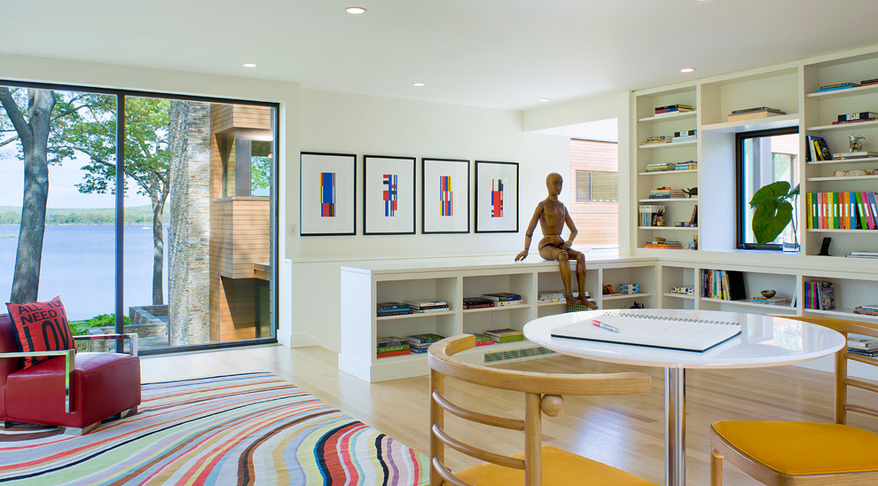 Immagine di un soggiorno moderno con libreria, pareti bianche e pavimento in legno massello medio
