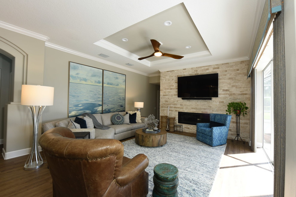 Cette image montre une grande salle de séjour traditionnelle ouverte avec un mur beige, un sol en vinyl, une cheminée standard, un téléviseur fixé au mur et un sol marron.