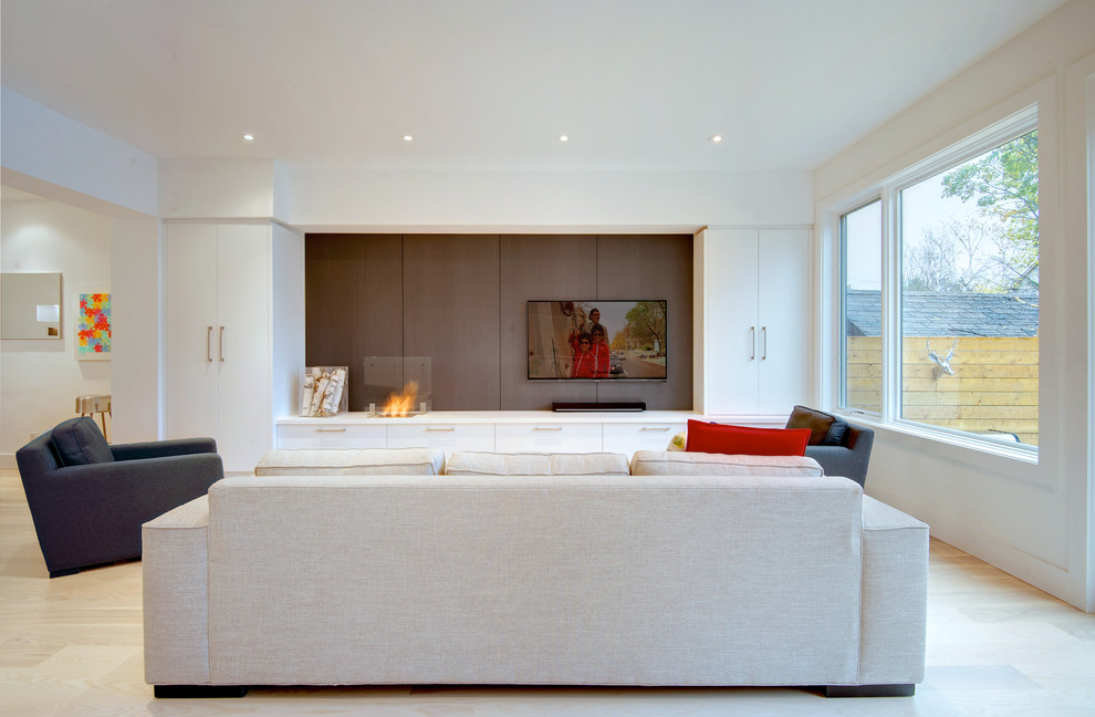 Diseño de sala de estar abierta contemporánea grande con paredes blancas, suelo de madera clara, chimenea lineal, marco de chimenea de madera y pared multimedia