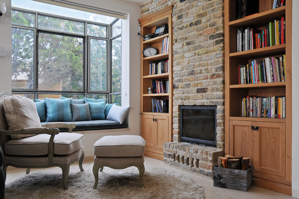 Aménagement d'une salle de séjour avec une bibliothèque ou un coin lecture, une cheminée standard, un manteau de cheminée en brique et aucun téléviseur.