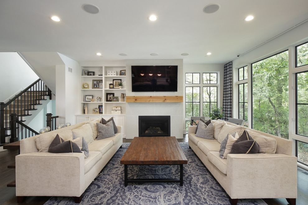 This is an example of a large classic open plan games room in Chicago with white walls, dark hardwood flooring, a standard fireplace, a stone fireplace surround, a wall mounted tv and brown floors.