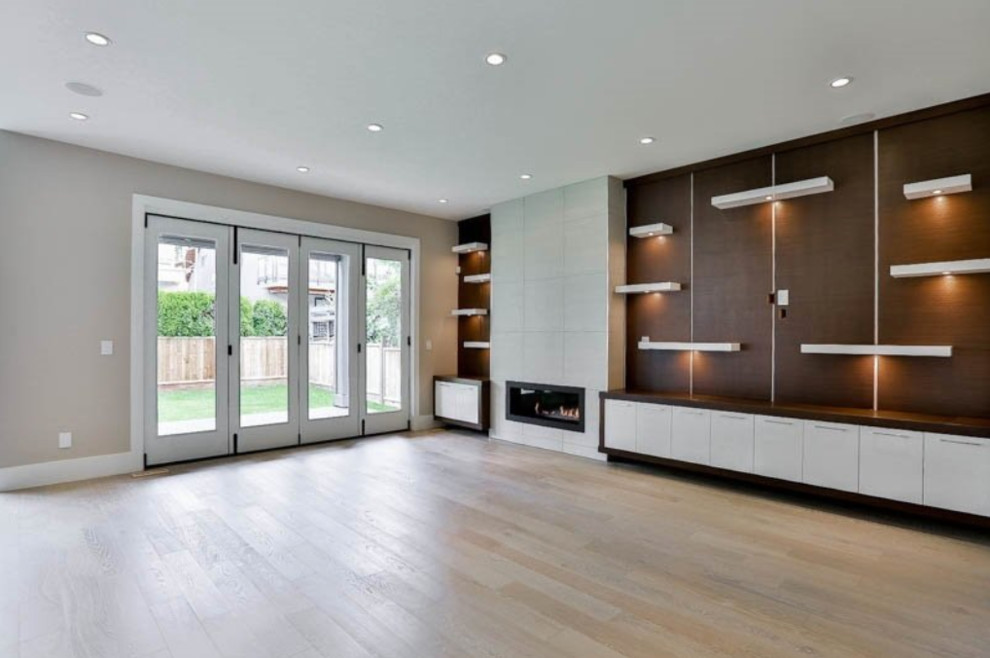 Offenes Modernes Wohnzimmer mit beiger Wandfarbe, hellem Holzboden, Gaskamin, gefliester Kaminumrandung und beigem Boden in Vancouver