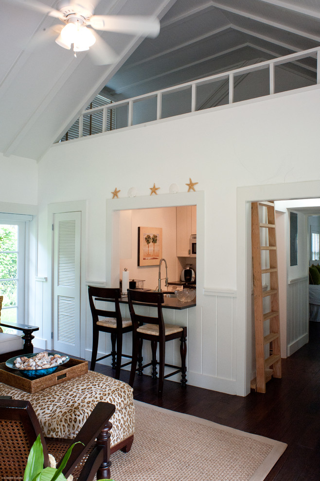 Ejemplo de sala de estar tropical de tamaño medio con paredes blancas y suelo laminado