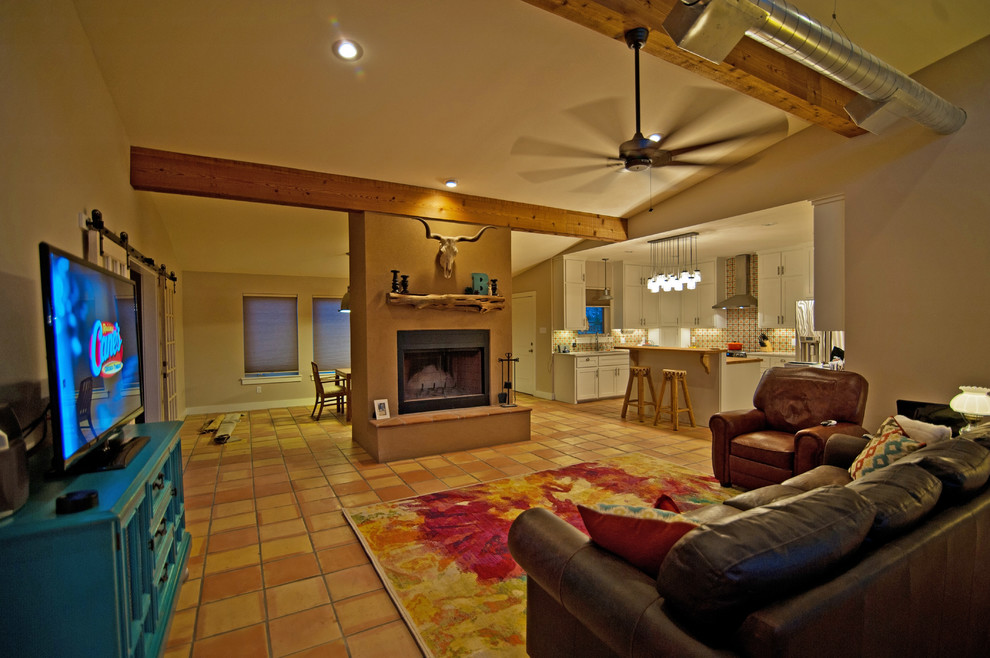 This is an example of a medium sized open plan games room in Austin with beige walls, terracotta flooring, a standard fireplace and a freestanding tv.