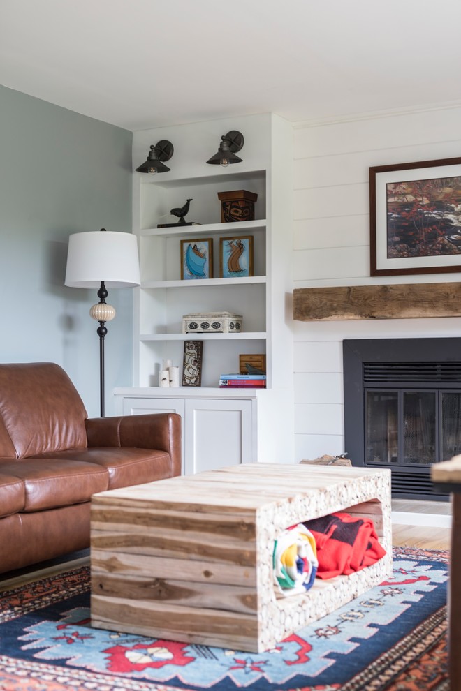 オタワにある高級な中くらいなラスティックスタイルのおしゃれな独立型ファミリールーム (青い壁、淡色無垢フローリング、標準型暖炉、木材の暖炉まわり、据え置き型テレビ) の写真
