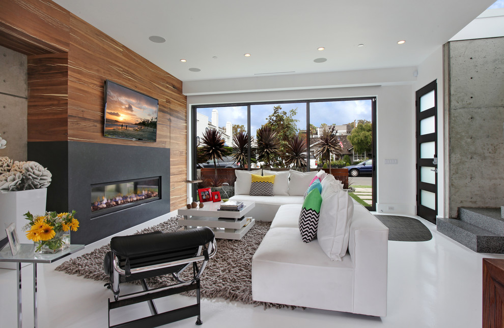 Imagen de sala de estar actual con paredes blancas, chimenea lineal y televisor colgado en la pared