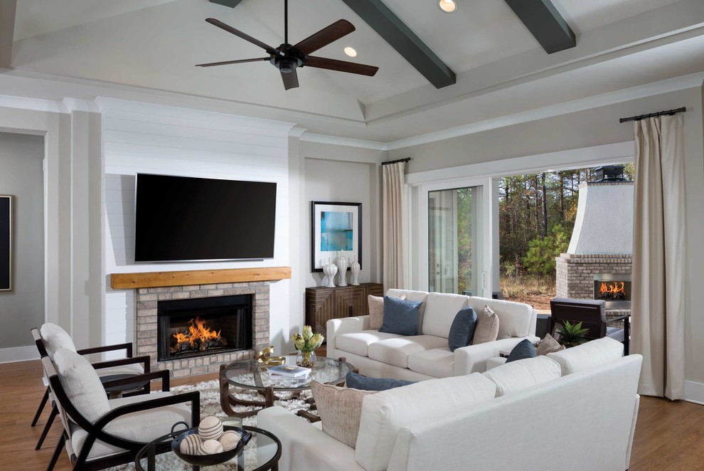 Design ideas for a beach style games room in Other with a wall mounted tv, grey walls, medium hardwood flooring, a ribbon fireplace and a brick fireplace surround.
