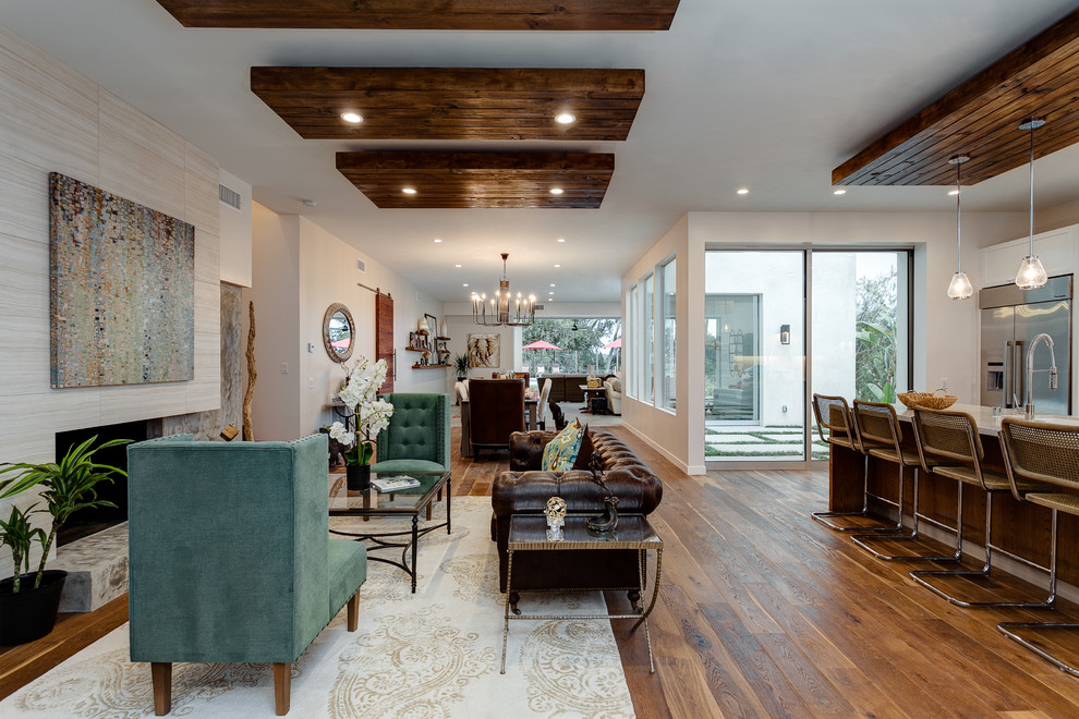 Foto de sala de estar abierta actual de tamaño medio con todas las chimeneas, suelo de madera en tonos medios, marco de chimenea de baldosas y/o azulejos y alfombra