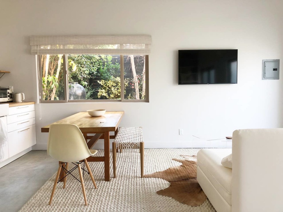 Mittelgroßer Moderner Hobbyraum ohne Kamin, im Loft-Stil mit weißer Wandfarbe, Betonboden, Kaminumrandung aus Beton, TV-Wand und grauem Boden in Los Angeles