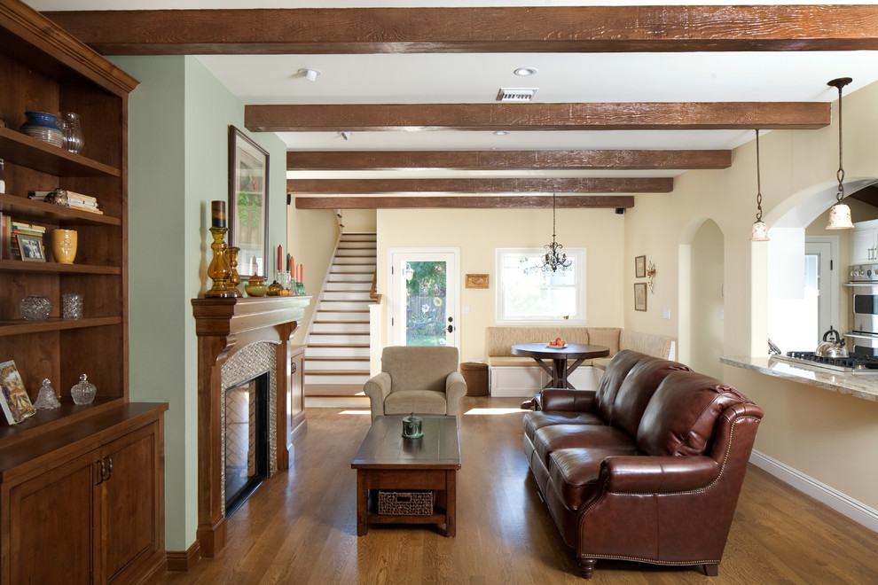 Diseño de sala de estar abierta tradicional de tamaño medio sin televisor con paredes beige, suelo de madera en tonos medios, todas las chimeneas y marco de chimenea de madera