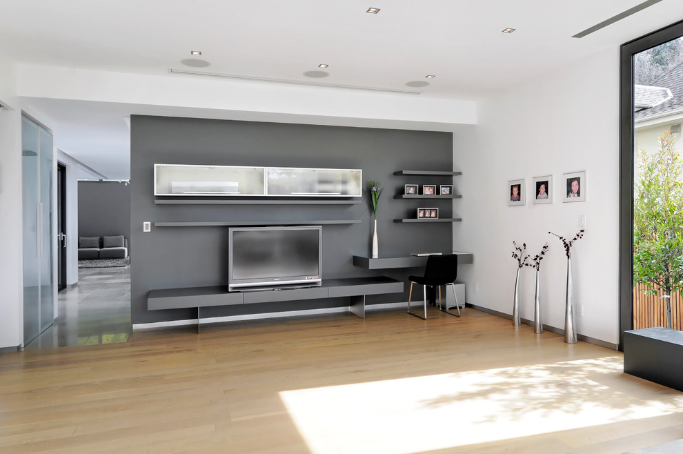 Imagen de sala de estar contemporánea con suelo de madera clara, televisor independiente y paredes multicolor