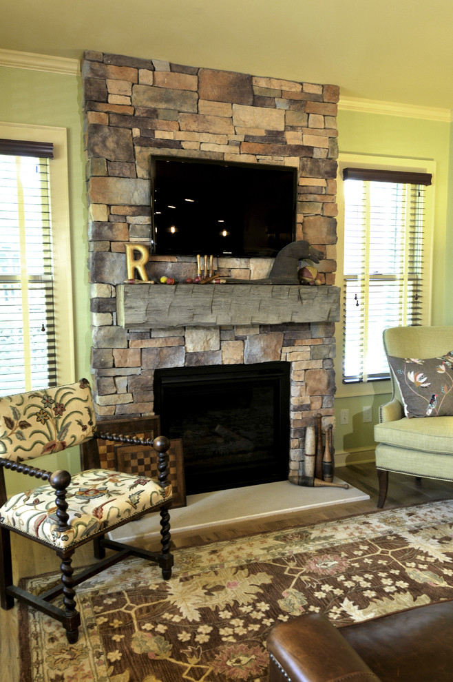Источник вдохновения для домашнего уюта: гостиная комната в классическом стиле с зелеными стенами, паркетным полом среднего тона, фасадом камина из камня, телевизором на стене и стандартным камином