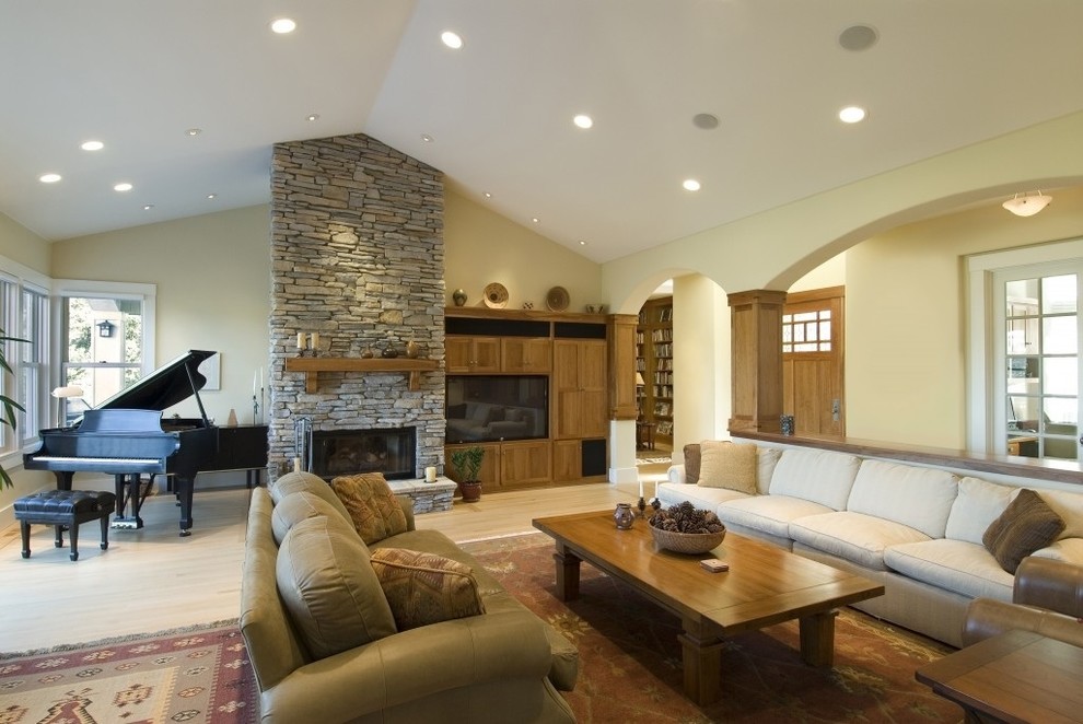 Modelo de sala de estar clásica renovada grande con paredes beige, suelo de madera clara, todas las chimeneas, marco de chimenea de piedra, pared multimedia y suelo beige