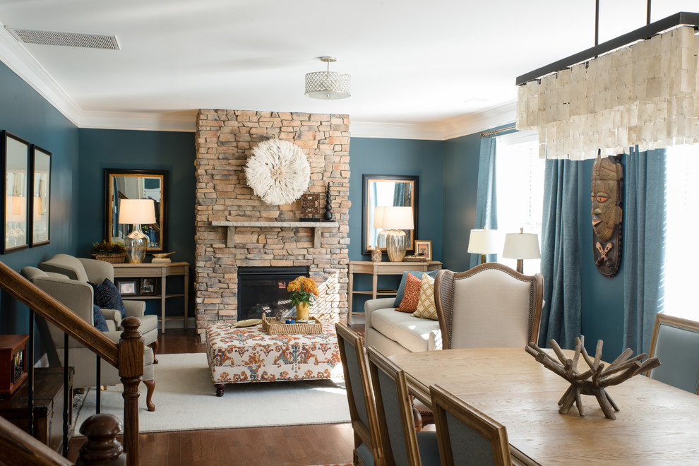 Réalisation d'une salle de séjour tradition de taille moyenne et ouverte avec un mur bleu, un sol en bois brun, une cheminée standard, un manteau de cheminée en pierre, aucun téléviseur et un sol marron.