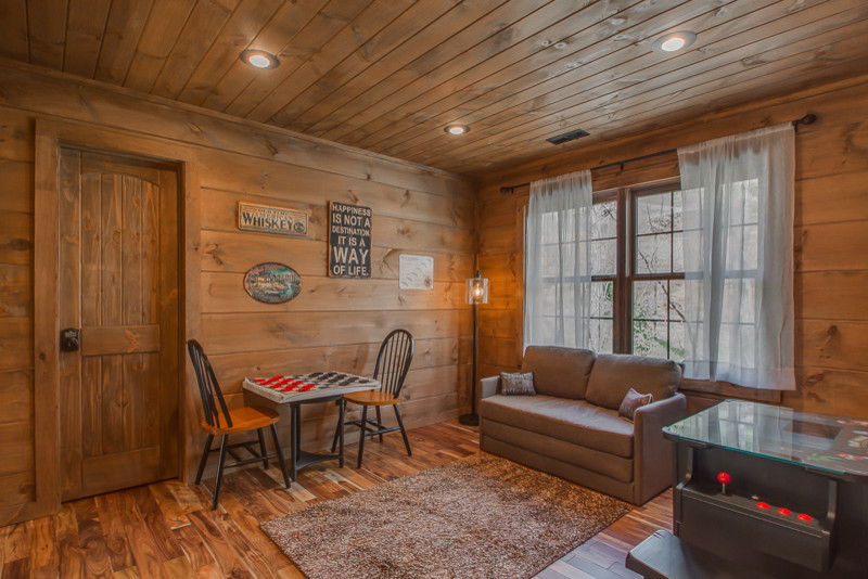 Ejemplo de sala de juegos en casa tipo loft rural de tamaño medio con paredes marrones, suelo de madera en tonos medios y suelo marrón