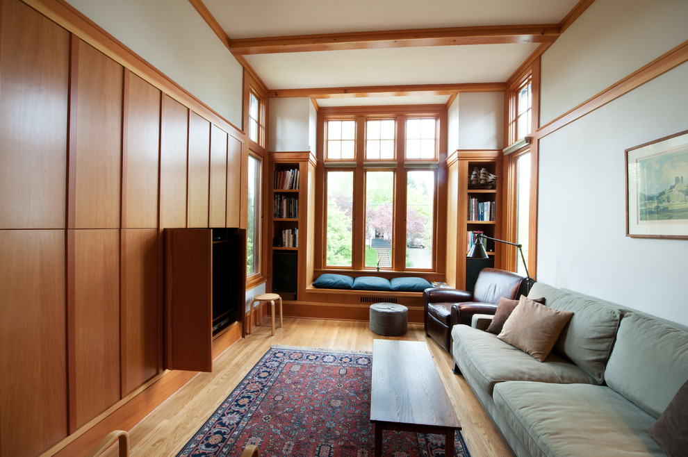 Abgetrenntes Modernes Wohnzimmer mit beiger Wandfarbe, braunem Holzboden und verstecktem TV in Portland