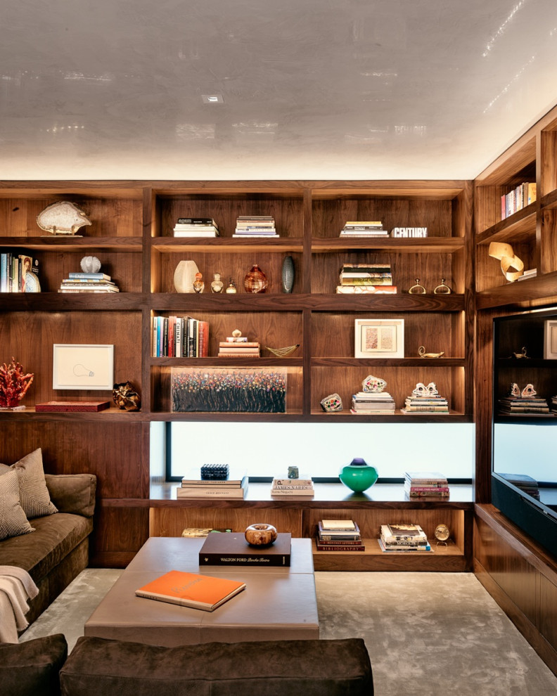 Imagen de sala de estar con biblioteca cerrada contemporánea de tamaño medio sin chimenea con paredes marrones, moqueta, marco de chimenea de piedra, pared multimedia y suelo gris