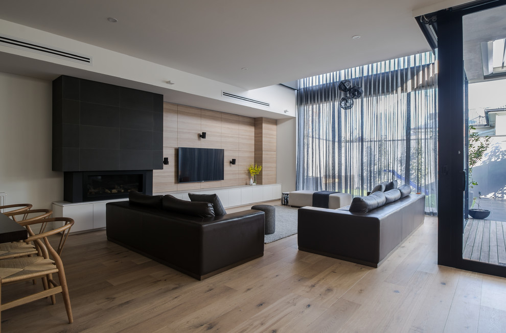 Ejemplo de sala de estar abierta minimalista de tamaño medio con suelo de madera en tonos medios, todas las chimeneas y marco de chimenea de piedra