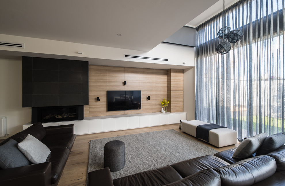 Foto de sala de estar abierta minimalista de tamaño medio con suelo de madera en tonos medios, todas las chimeneas y marco de chimenea de piedra