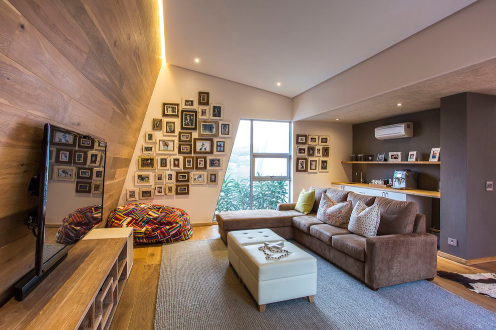 Modernes Wohnzimmer mit brauner Wandfarbe, braunem Holzboden und freistehendem TV in Sonstige