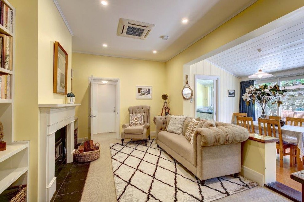 Idée de décoration pour une salle de séjour champêtre de taille moyenne et ouverte avec un mur jaune, moquette, un poêle à bois, un manteau de cheminée en plâtre et un sol beige.