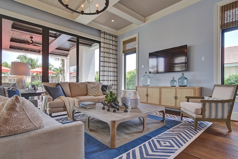 Esempio di un ampio soggiorno chic aperto con pareti blu, pavimento in legno massello medio e TV a parete