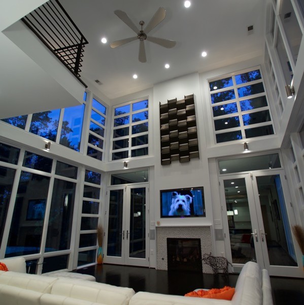 Стильный дизайн: большая двухуровневая комната для игр в современном стиле с серыми стенами, темным паркетным полом, двусторонним камином, фасадом камина из плитки и телевизором на стене - последний тренд