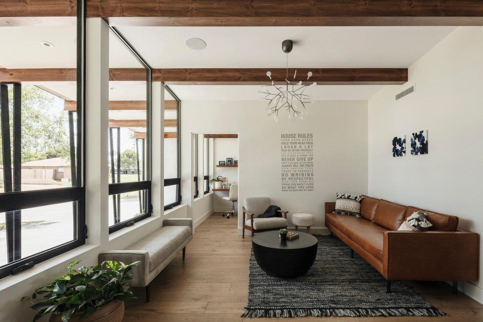 Ejemplo de sala de estar abierta retro con paredes blancas, suelo de madera en tonos medios, televisor colgado en la pared y vigas vistas