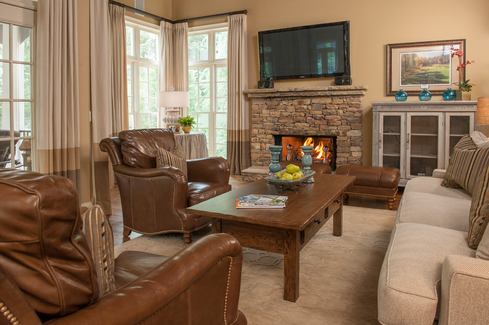 Mid-sized elegant open concept medium tone wood floor and brown floor family room photo in Atlanta with beige walls, a standard fireplace, a stone fireplace and a wall-mounted tv