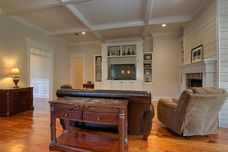 Cette image montre une grande salle de séjour traditionnelle ouverte avec un mur blanc, un sol en bois brun, une cheminée standard, un manteau de cheminée en bois et un téléviseur indépendant.