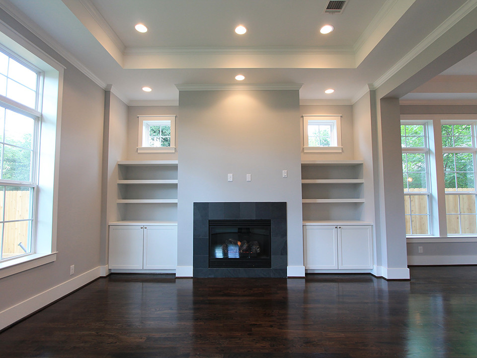 Offenes Klassisches Wohnzimmer mit grauer Wandfarbe, dunklem Holzboden, Kamin und gefliester Kaminumrandung in Houston